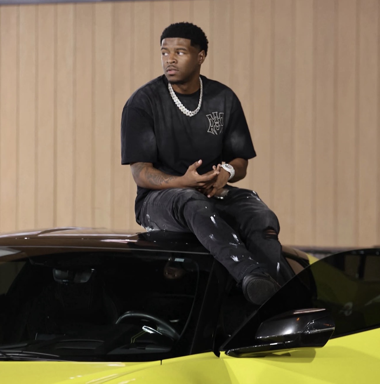 Creator sitting on a black and neon-yellow sports car